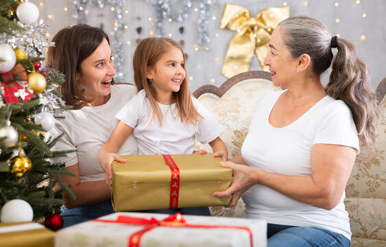Grandmother mom and daughter holding gift in Christmas interior