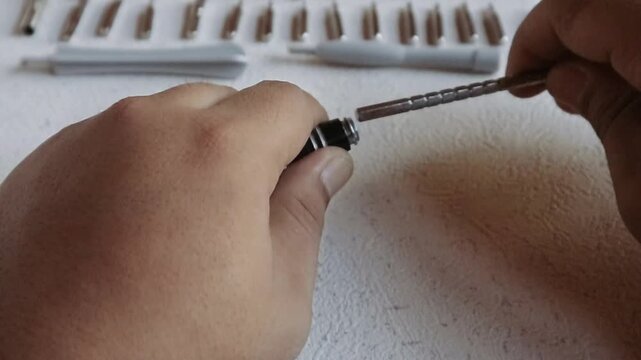 This video shows the hand of an Asian person attaching a screwdriver extension that serves as a holder for the screwdriver bit.