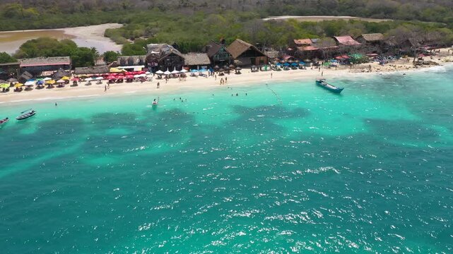 Vibrant Coastal Landscape of Playa Blanca, Baru, Colombia: Aerial Photography Showing the Luminous Green-Blue Sea, Dense Mangrove Forest in the Background, and Lively Beachfront Huts