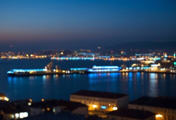 Naklejka premium Vibrant city skyline at twilight with illuminated buildings and sparkling water reflections