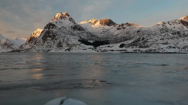 View of mountains full of snow in winter time with lake frozen in Lofoten at sunset, Norway