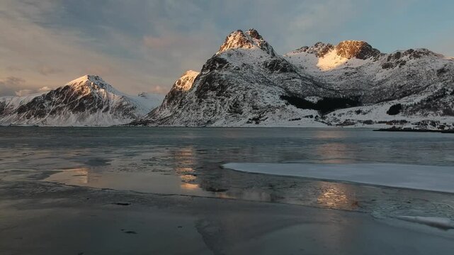 View of mountains full of snow in winter time with lake frozen in Lofoten at sunset, Norway