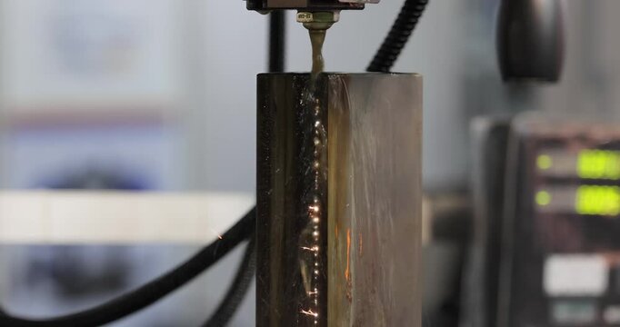 Wire EDM cutting of metal workpiece with sparks in industrial machine.