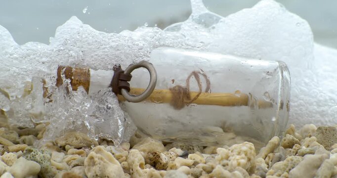 Message in the bottle on a sand beach. Shot on super slow motion camera 1000 fps.