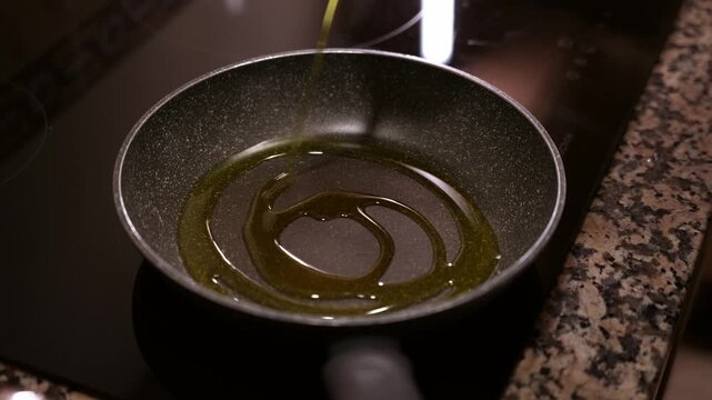 Pouring olive oil into pan on induction stove. Cooking healthy food.