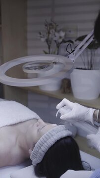 Careful facial treatment performed by gloved hands under ring light
