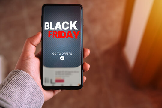 Black Friday sale offer on smartphone screen held by hand. Woman hand showing Black Friday offer on phone.