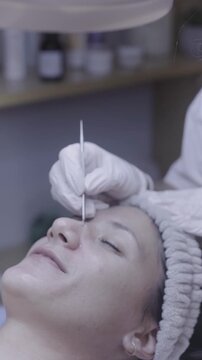Fine brush applying serum to relaxed skin during facial ritual