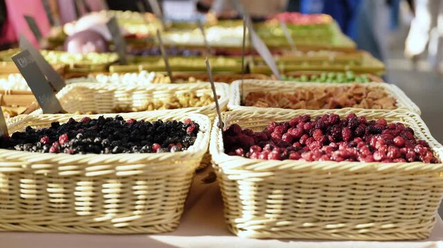 Colorful dried berries and fruits in wicker baskets at a bustling street market stall