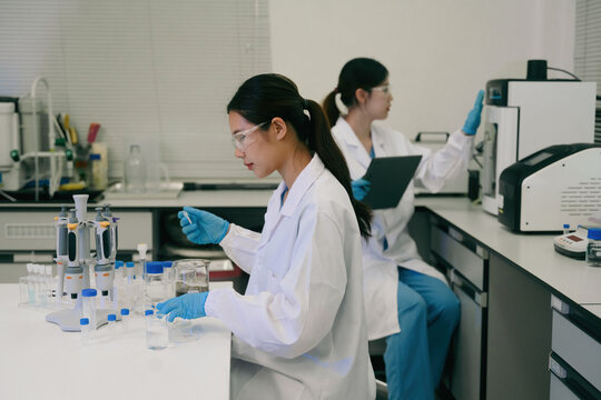 Asian Female Scientists Working in Modern Research Laboratory with Pipettes and Lab Equipment