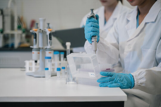 Close up of Female Scientist Using Micropipette in Research Laboratory with Vials and Lab Equipment