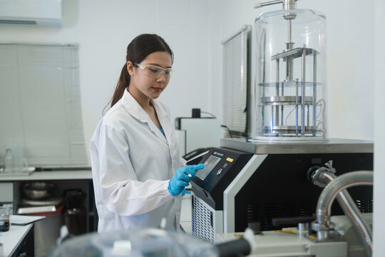 Asian Female Scientist Operating Freeze Dryer Machine in Modern Research Laboratory