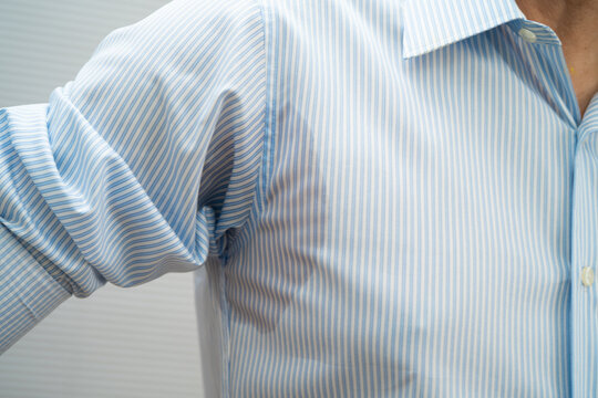 Man with sweat on clothes under armpit when working in office.