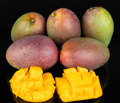 Yellow mango slices on red fruits background