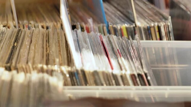 Hand browsing collection of vinyl records, searching for music in a vintage store