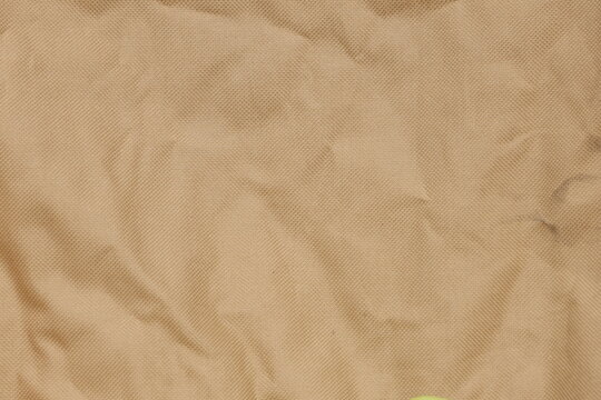 Beige canvas tarpaulin texture with natural fabric folds, neutral background for creative design