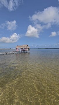 Scenic tropical lagoon surrounded by mangrove forest in Rio Lagartos, Yucatan, Mexico, with traditional thatched palapas and wooden pier under a dramatic cloudy blue sky. Peaceful ecotourism destinati