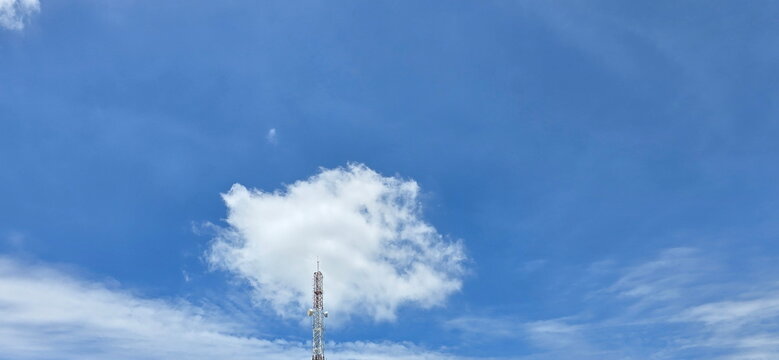 The sky was clear blue with large white clouds floating above the tops of telecommunication tower structures. Cumulus is a fluffy, cotton-like mass or cauliflower-like growth. Fair-weather cumulus

