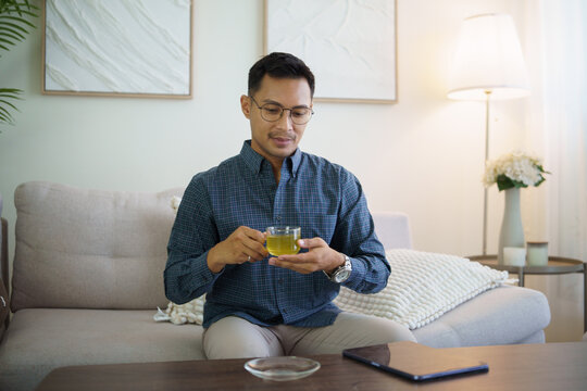 Asian man enjoying tea during a relaxing break at home.