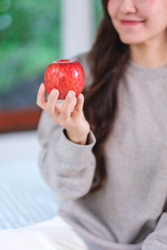 Vertical closeup image of a woman holding a red apple