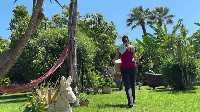 Mujer llevando cesta con ropa por el jard&iacute;n