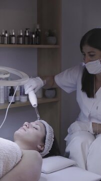 Handheld device mists calming vapor over relaxed skin in spa treatment