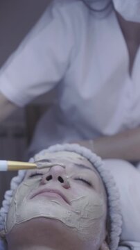 Gentle brush strokes apply clay mask along the cheek in calm facial ritual