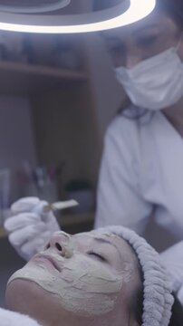 Steady hand paints clay mask across relaxed skin in spa ritual