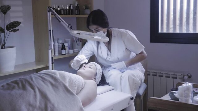 Focused skincare professional preparing client for facial treatment
