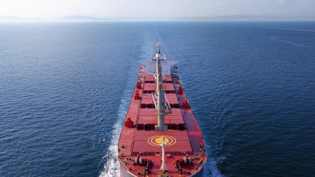Aerial top view of a general cargo vessel passing by and sailing with high speed over the ocean