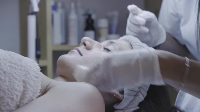 Calm client receiving soothing facial massage with gloved hands