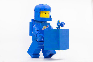 Fototapeta premium Hong Kong, June 8, 2026: A classic blue LEGO spaceman carries a blue brick block, symbolizing a playful gift of building element.
