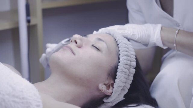 Ultrasonic skin scrubber gliding across a relaxed face in a calm facility