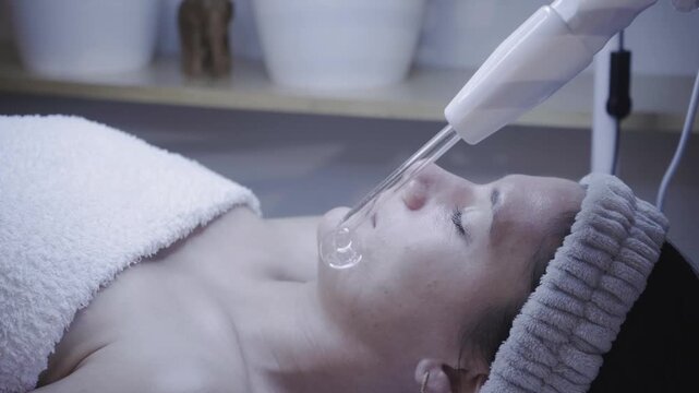 Glass tool releasing a clear drop above the nose during a soothing facial