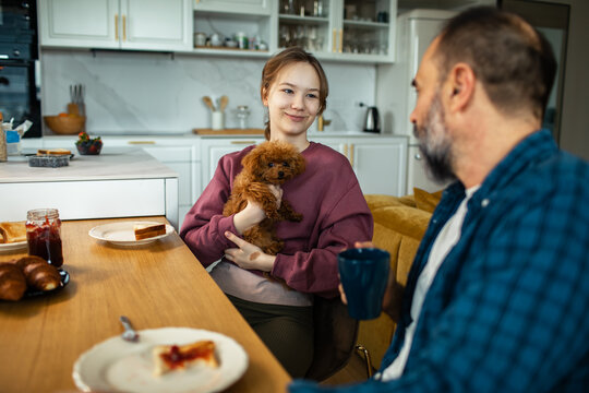 Young woman holding puppy at breakfast in modern kitchen