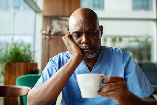 Mature nurse drinking coffee during break in hospital cafeteria