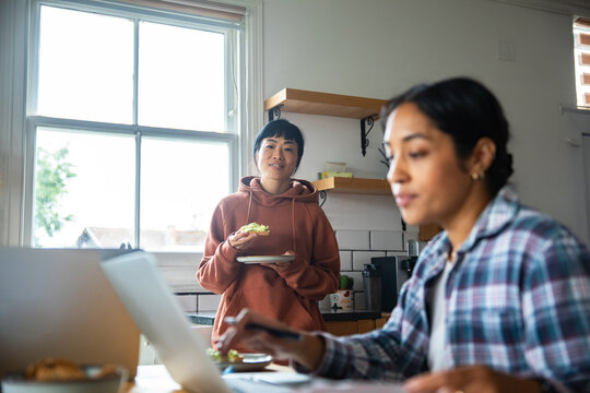 Two women working from home in bright kitchen