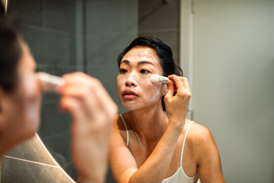 Woman applying face mask in bathroom at home