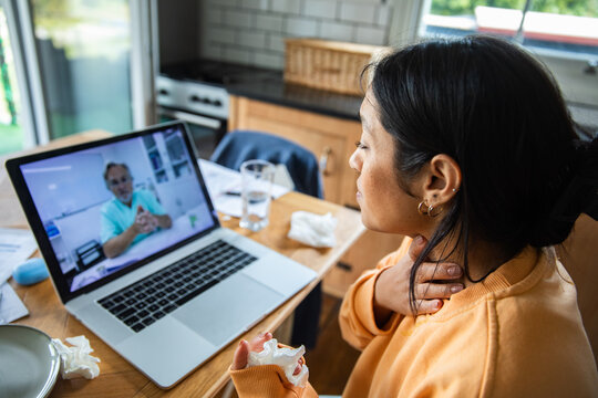 Young woman on telehealth video consultation in home kitchen