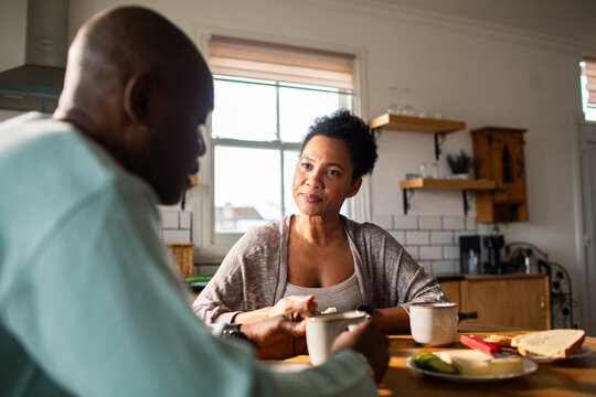 Middle-aged couple talking over coffee in home kitchen