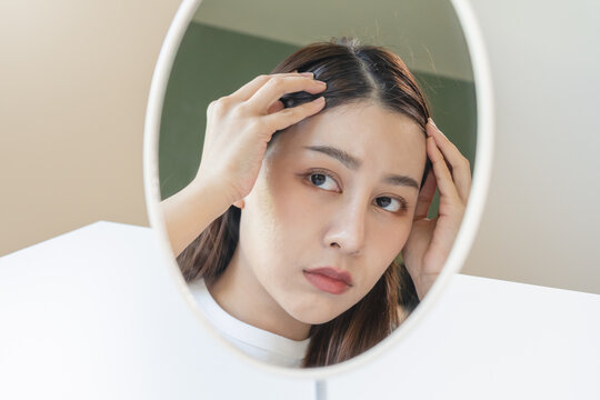 Hair loss problem, Asian woman look at scalp worry about balding.