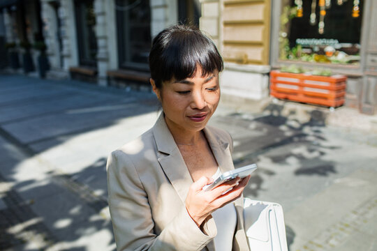 Businesswoman using smartphone on city street