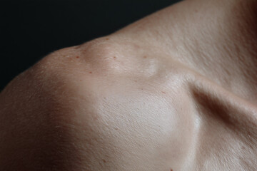 Fototapeta premium Close up shoulder skin fold smooth surface small mole blemish natural texture subtle hair lighting calm