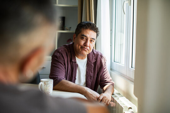 Thoughtful man having a serious conversation at home by the window