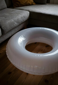 Summer vacation anticipation and indoor leisure, white inflatable swimming ring on wooden floor in a living room