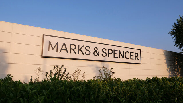 Leicester, England, UK - 17 July 2026: Marks and Spencer department store sign mounted on white exterior wall above green bushes