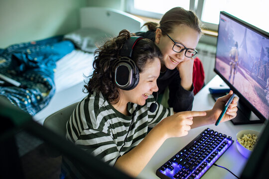 Two friends gaming with headset and smartphone at home