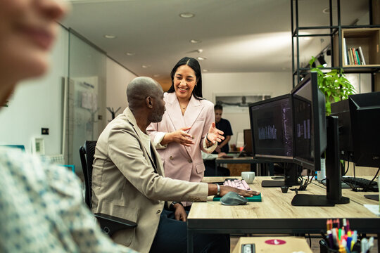 Coworkers discussing code at modern office workstation