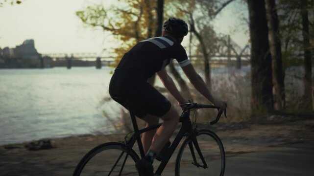 Cyclist Riding Road Bike On Path Near River Bank With Bridge 