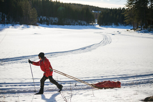 Active female pulling sled while skiing on snowy landscape at tranquil remote location